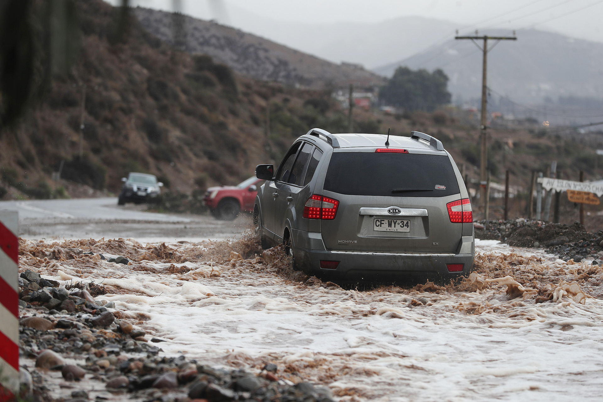 A vehicle drives through a flooded road after Los Loros Creek overflowed in La Serena, Chile, July 20, 2026. /VCG