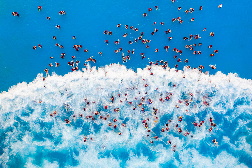 An aerial photo shows visitors enjoying waves in an artificial wave pool at a water park in Zhengzhou, Henan Province on July 22, 2026. /VCG