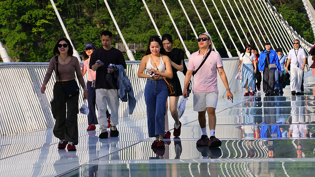 Visitors walk along the high-altitude glass bridge at Zhangjiajie National Forest Park in Hunan Province, central China, May 11, 2026. /VCG