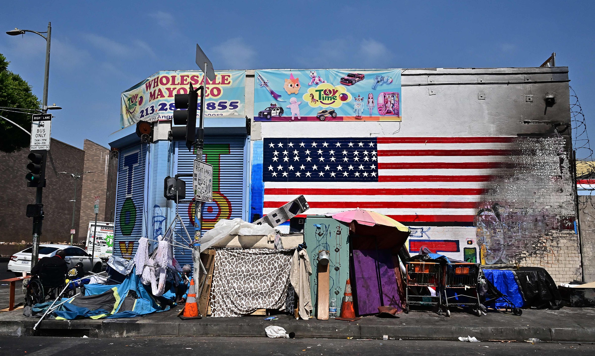 The flag of the United States is seen partially destroyed on a wall behind a homeless encampment in Los Angeles, California, August 13, 2025. /CFP
