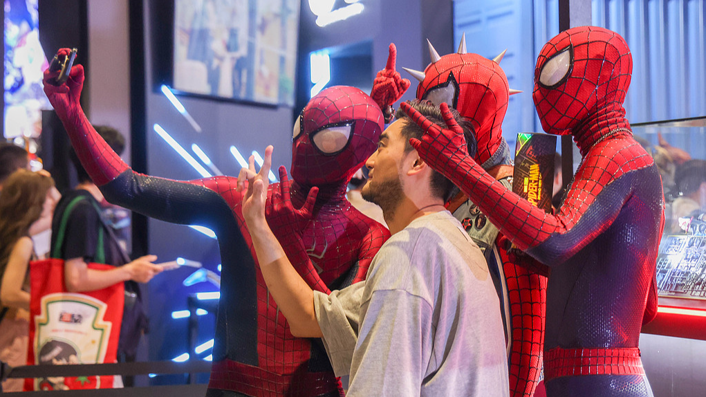 Visitors pose with men dressed as Spider-Man at a pop culture event in Shanghai on July 10, 2026. /VCG