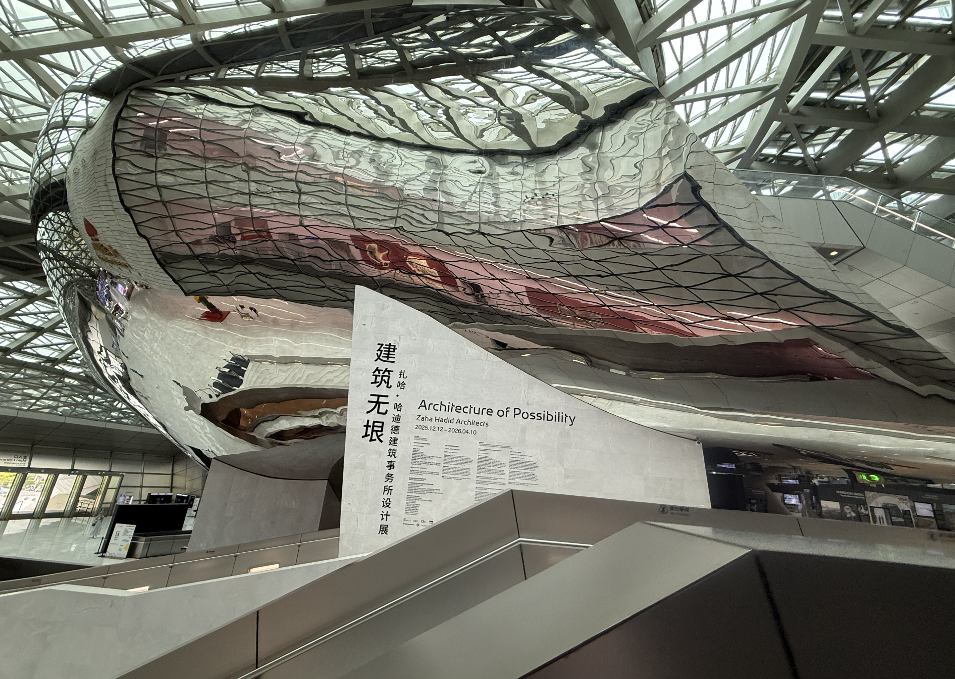 Inside MOCAUP, a look up at the museum's signature mirrored, wave-like volume suspended beneath the skylit roof.
