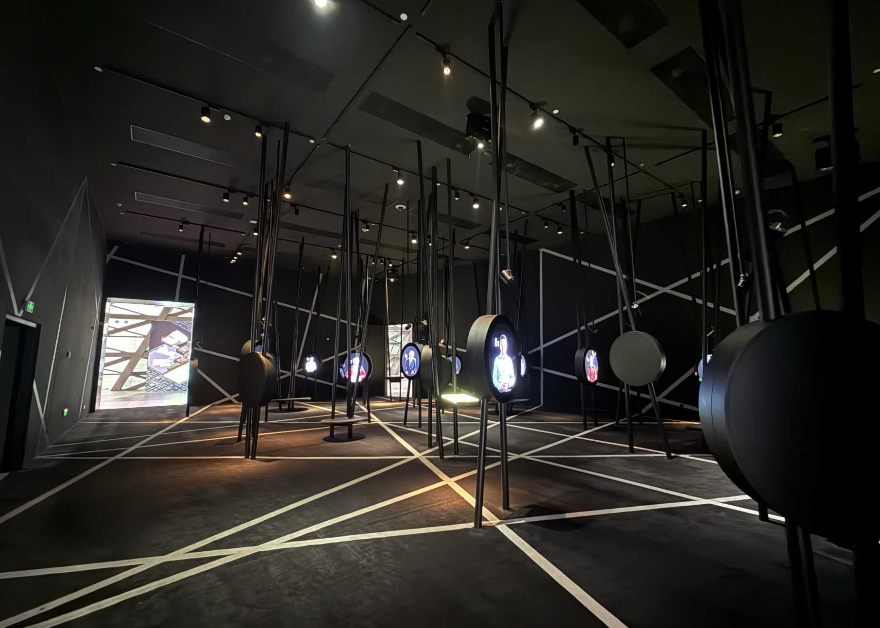 One of the museum's immersive galleries, a forest of suspended screens, each playing footage of a different Shenzhen resident, strung across a floor. 