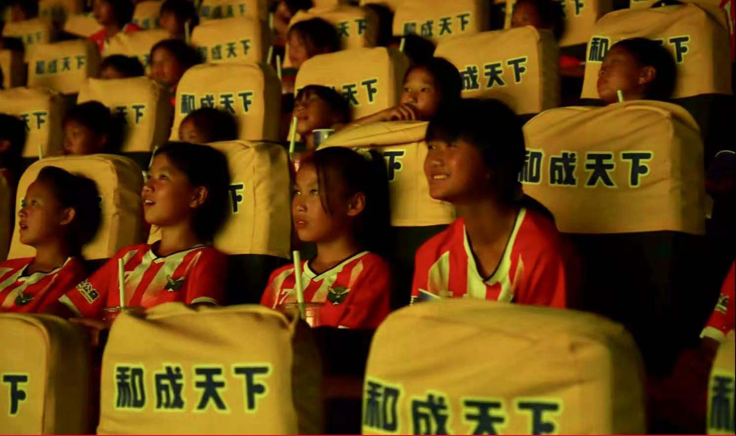 Young female football players from the Yuanbao Tongxin Experimental School team in southwest China's Guizhou Province watch the hit movie 
