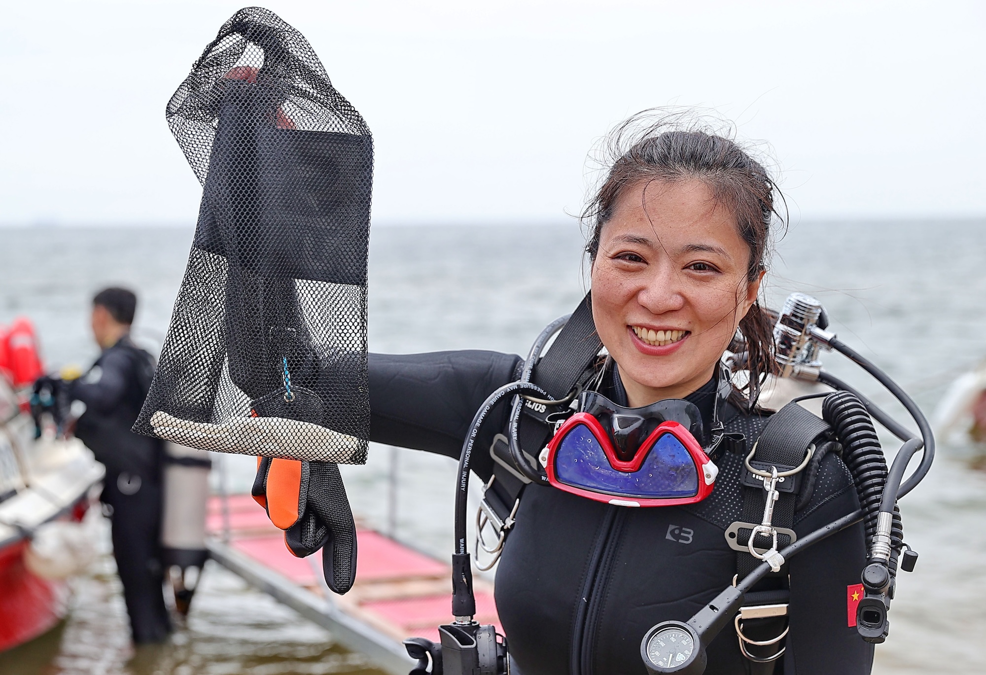 A volunteer diver displays the marine debris she collected during the 