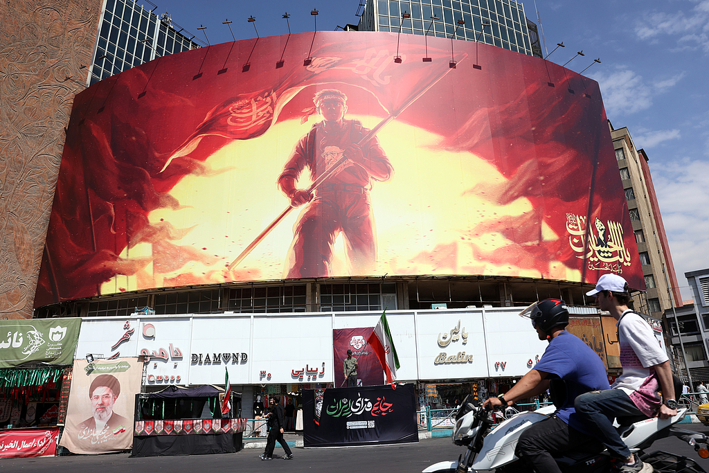 Iranians drive past a large political billboard at Valiasr Square in Tehran, Iran, August 1, 2026. /VCG