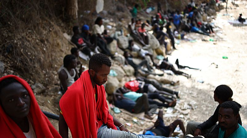 Migrants sit outside a short-stay migrant center in the Spanish North African enclave of Ceuta, August 1, 2026. /VCG