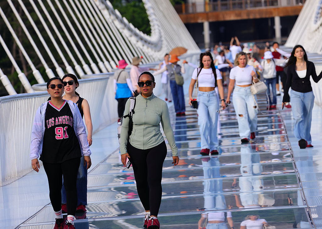 Foreign visitors walk across the glass bridge at Zhangjiajie Grand Canyon Scenic Area in Zhangjiajie City, central China's Hunan Province, May 11, 2026. /VCG