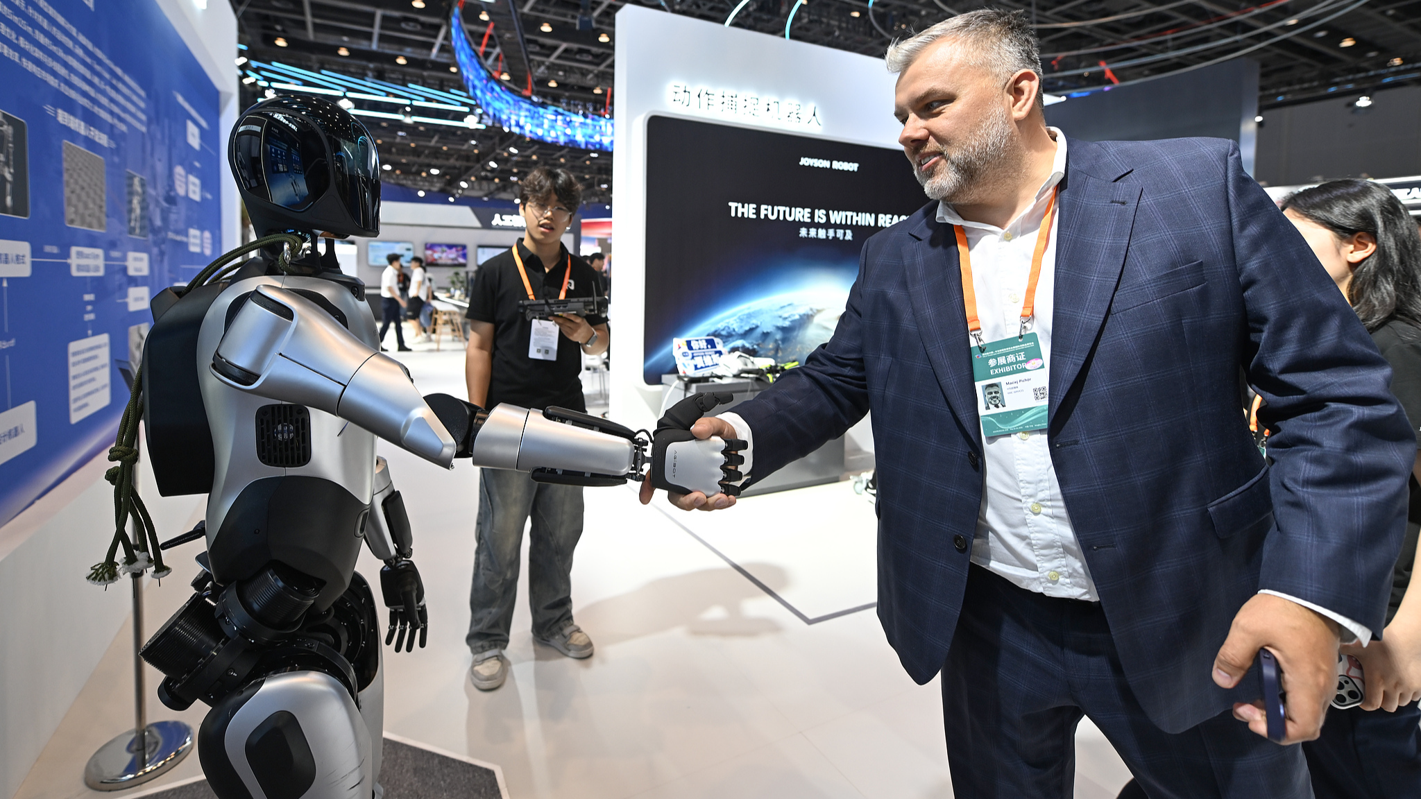 A European visitor shakes hands with a humanoid robot during an exhibition in Ningbo, Zhejiang Province, east China, May 22, 2025. /CFP