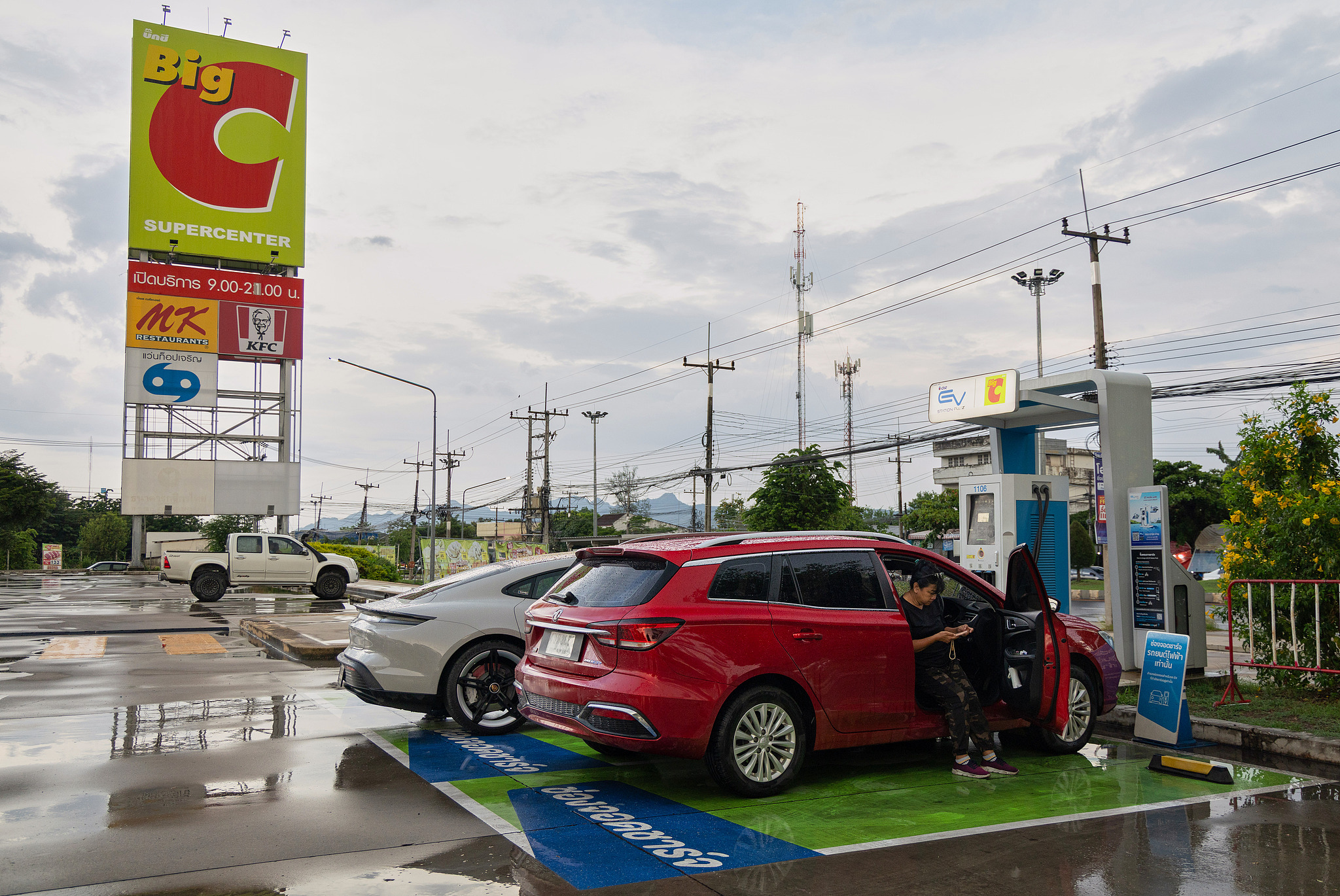 A Thai woman waits for her Chinese-made electric vehicle to charge at a gas station in Kanchanaburi, Thailand, May 30, 2026. /VCG