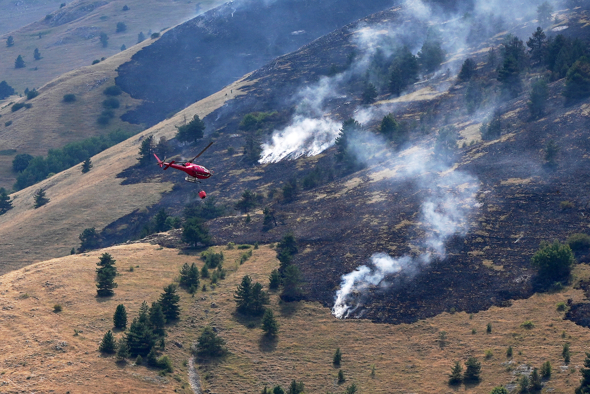 A firefighting helicopter flies toward a wildfire on a mountain near L'Aquila, central Italy, August 3, 2026. /VCG