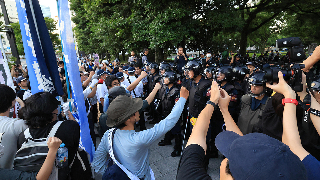 Police officers remove anti-war activists out at Hiroshima Peace Memorial Park in Hiroshima, Japan, August 6, 2026. /VCG