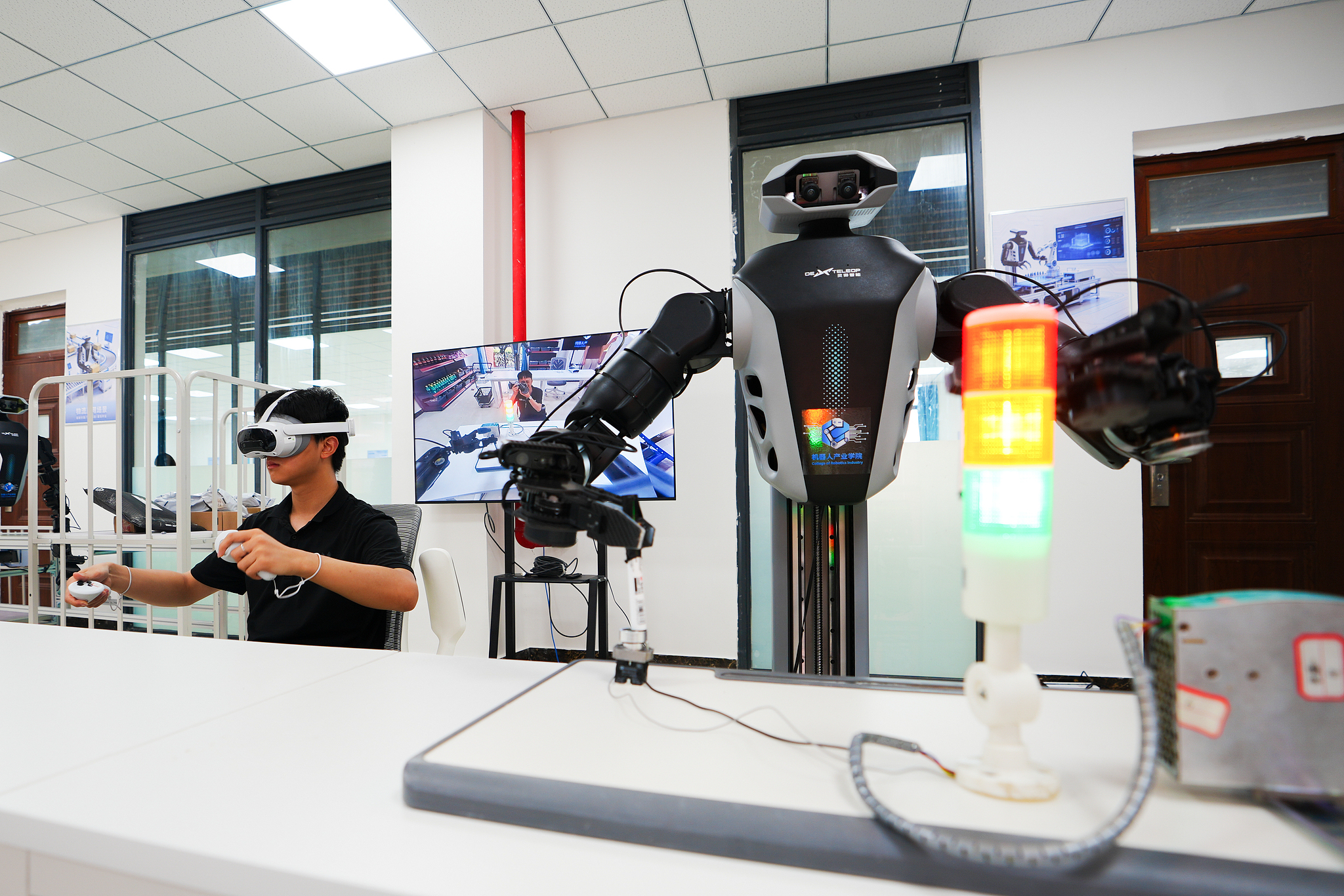 A student at Sichuan University of Science and Technology operates a robot to simulate power workers conducting circuit tests, Meishan, Sichuan Province, China, June 30, 2026. /VCG