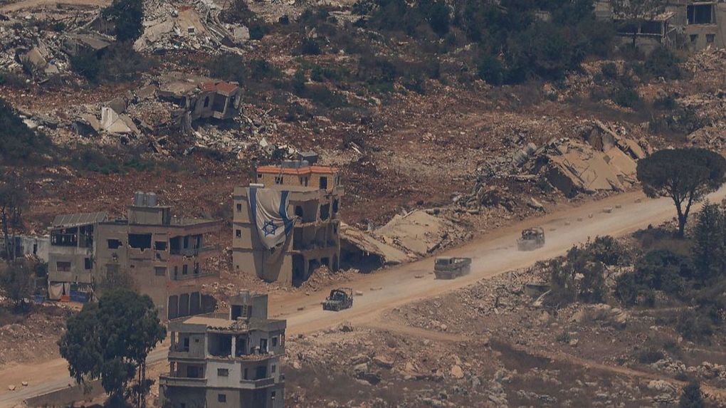 Israeli military vehicles drive past houses destroyed by Israeli strikes in southern Lebanon as seen from a position across the border in the Upper Galilee in northern Israel, July 22, 2026. /VCG