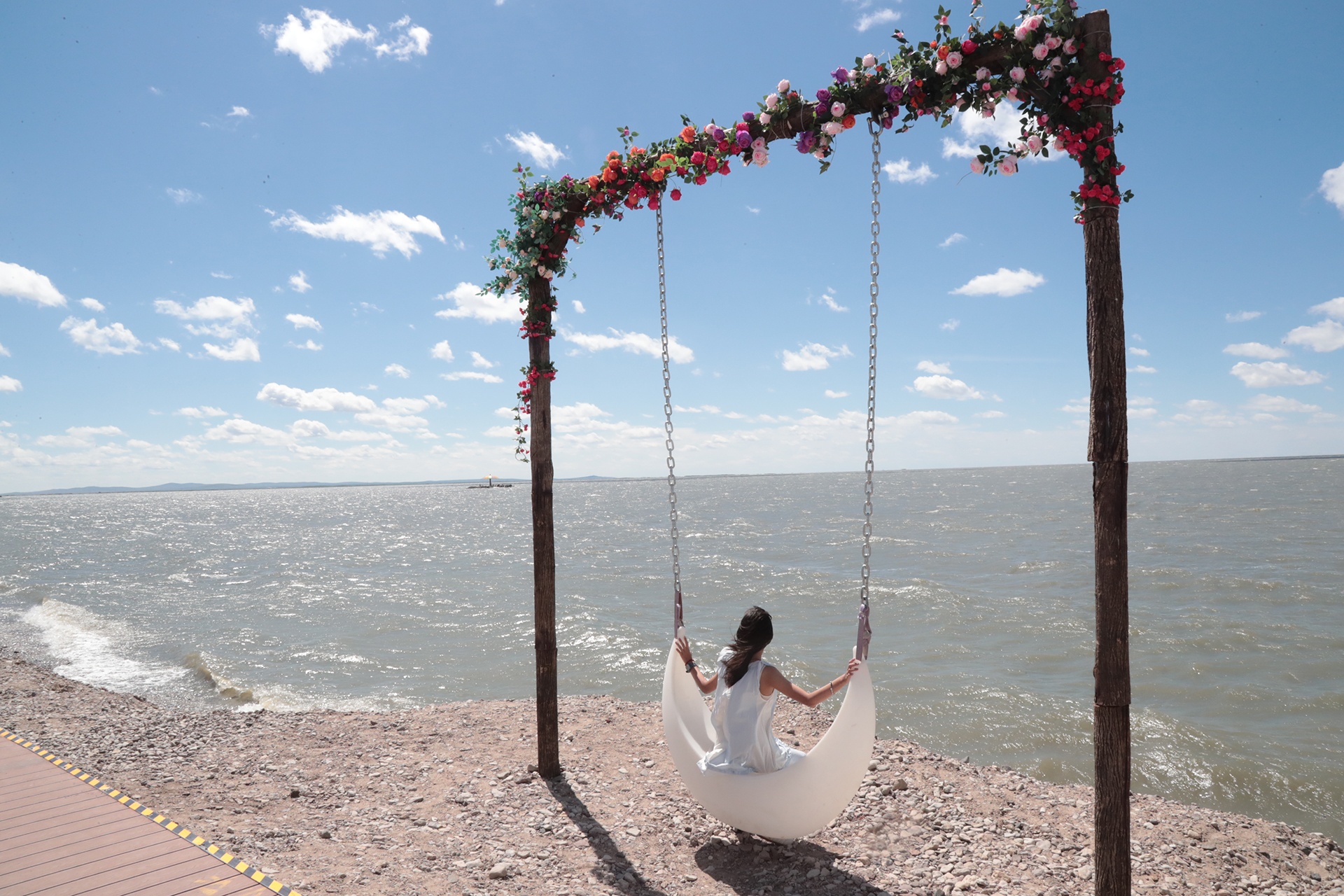 A visitor poses for photos on a swing by the shore of Hulun Lake in Hulunbuir, Inner Mongolia. /CGTN