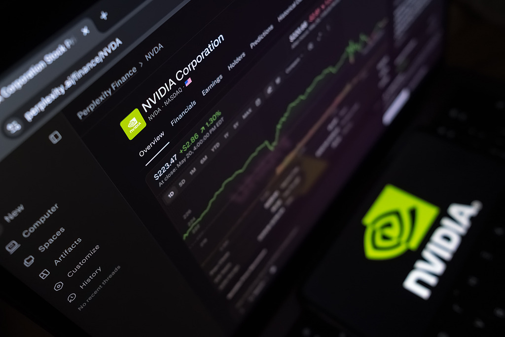 The Nvidia logo appears on a smartphone screen, with a stock exchange curve chart displayed as the background on a laptop computer screen in this photo illustration in Athens, Greece, on May 21, 2026. /VCG