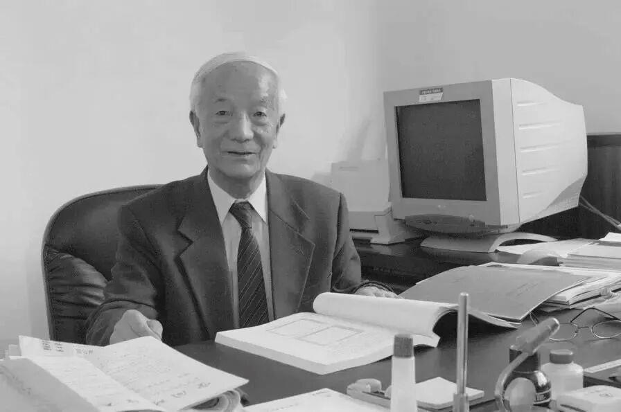 Wang Xiji sits at his desk with technical documents in his office. /CMG