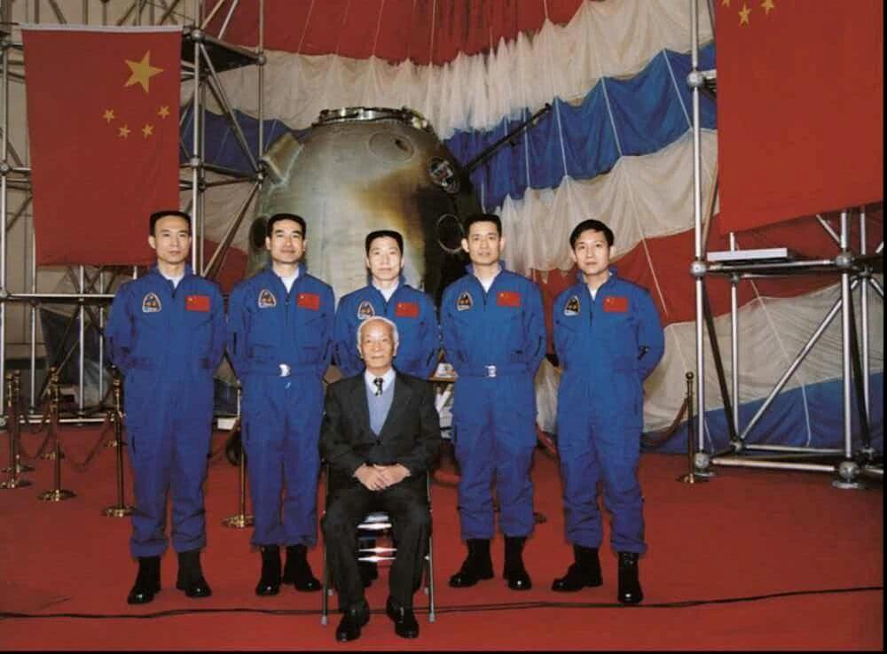 Wang Xiji poses with astronauts in front of the return capsule of the Shenzhou-5 spacecraft. /CMG