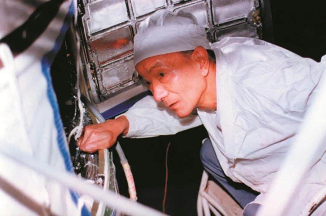 Wang Xiji inspects the installation of components inside a recoverable satellite. /CMG