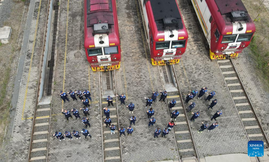 Railway workers from China and Kenya stand in front of locomotives and form the number 
