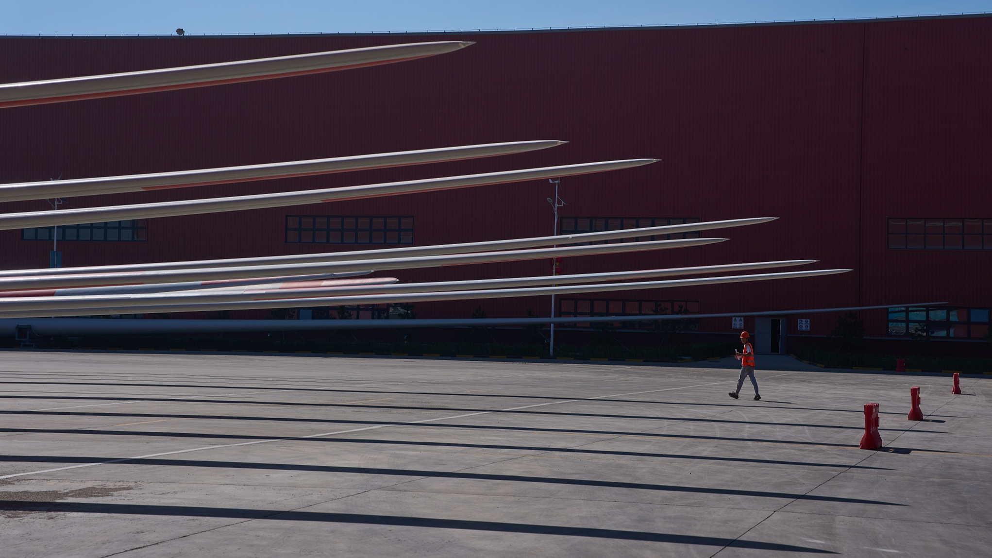 A worker walks near wind turbine blades at the Mingyang North Smart Energy factory near Baotou in northern China's Inner Mongolia Autonomous Region, June 13, 2026. /CFP