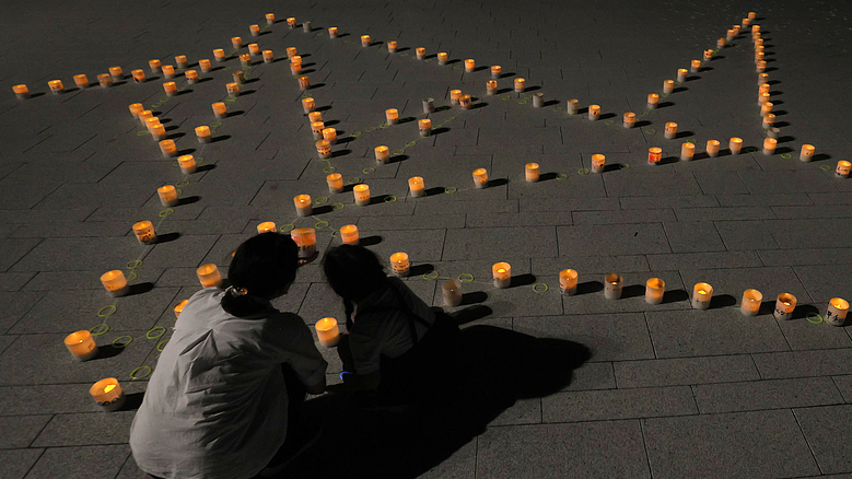 A parent and child look at LED candles arranged in the shape of an origami crane at Hiroshima Peace Memorial Park in Hiroshima City, Hiroshima Prefecture, Japan, August 6, 2026, the 81st anniversary of the US atomic bombing of Hiroshima. /VCG