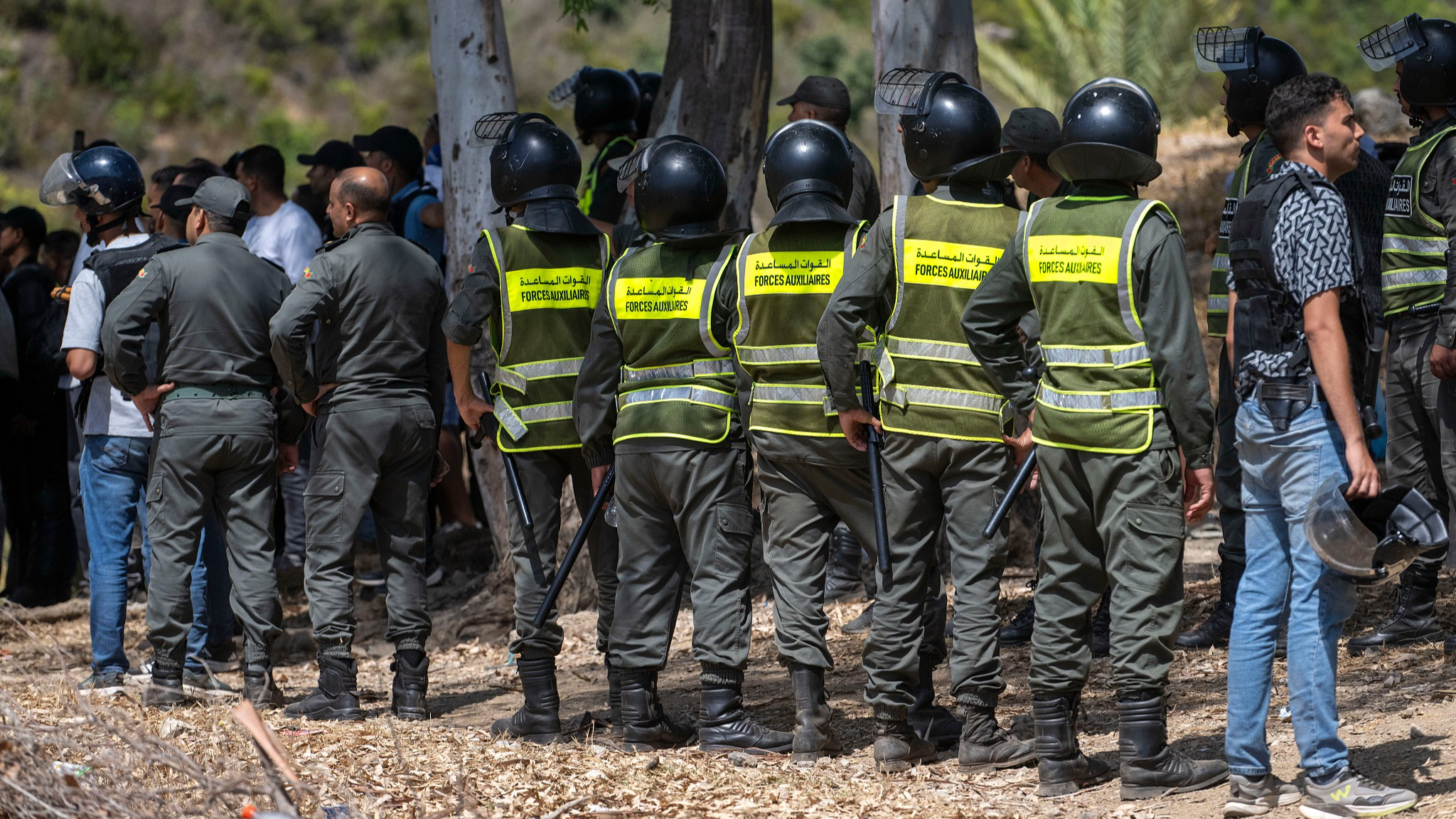 Moroccan security forces stand guard as migrants gather on a hill attempting to cross from the border town of Fnideq to the Spanish enclave of Ceuta, August 15, 2026. /VCG