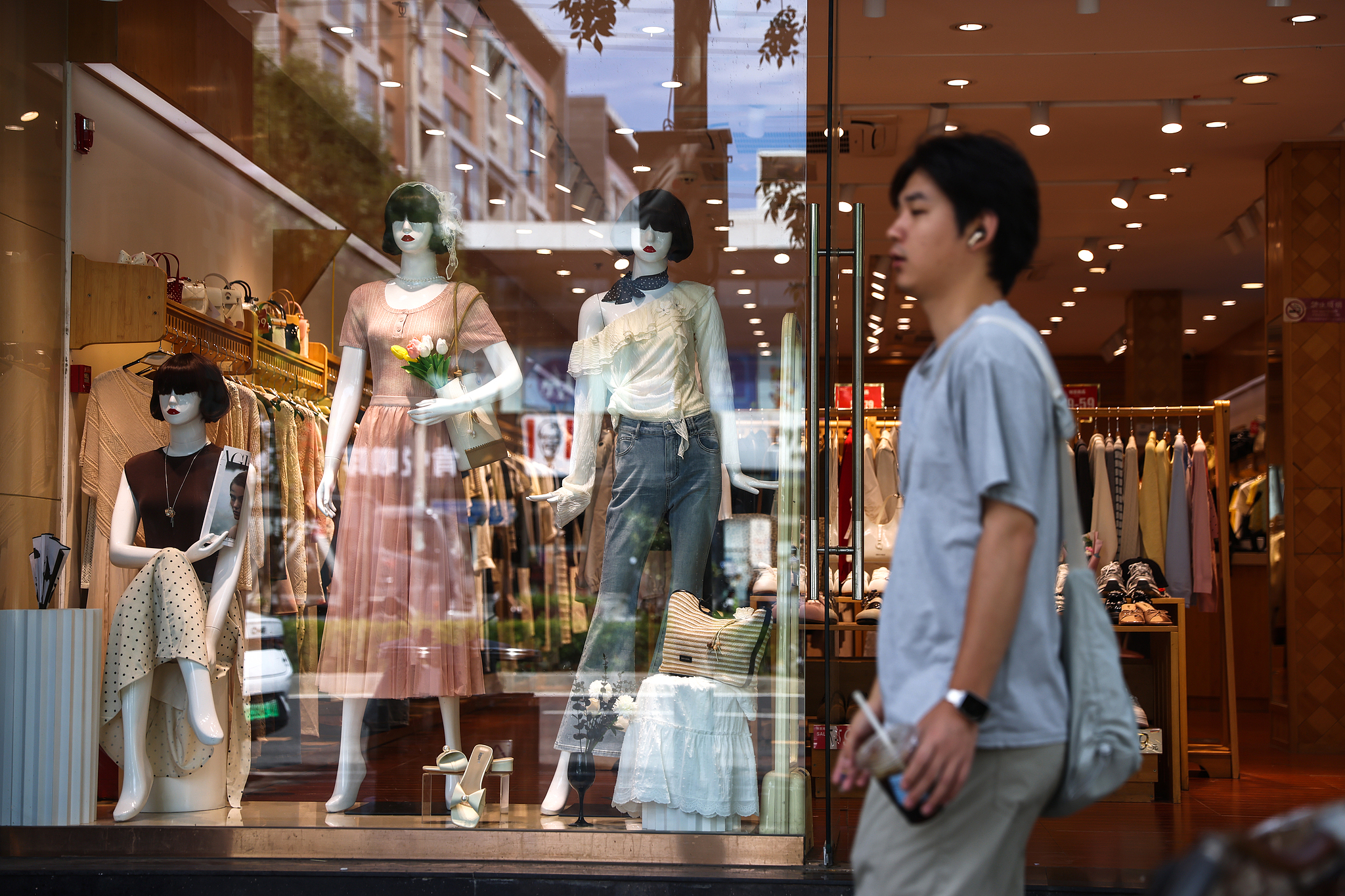 A person walks past a clothing store in Beijing, China, August 17, 2026. /VCG
