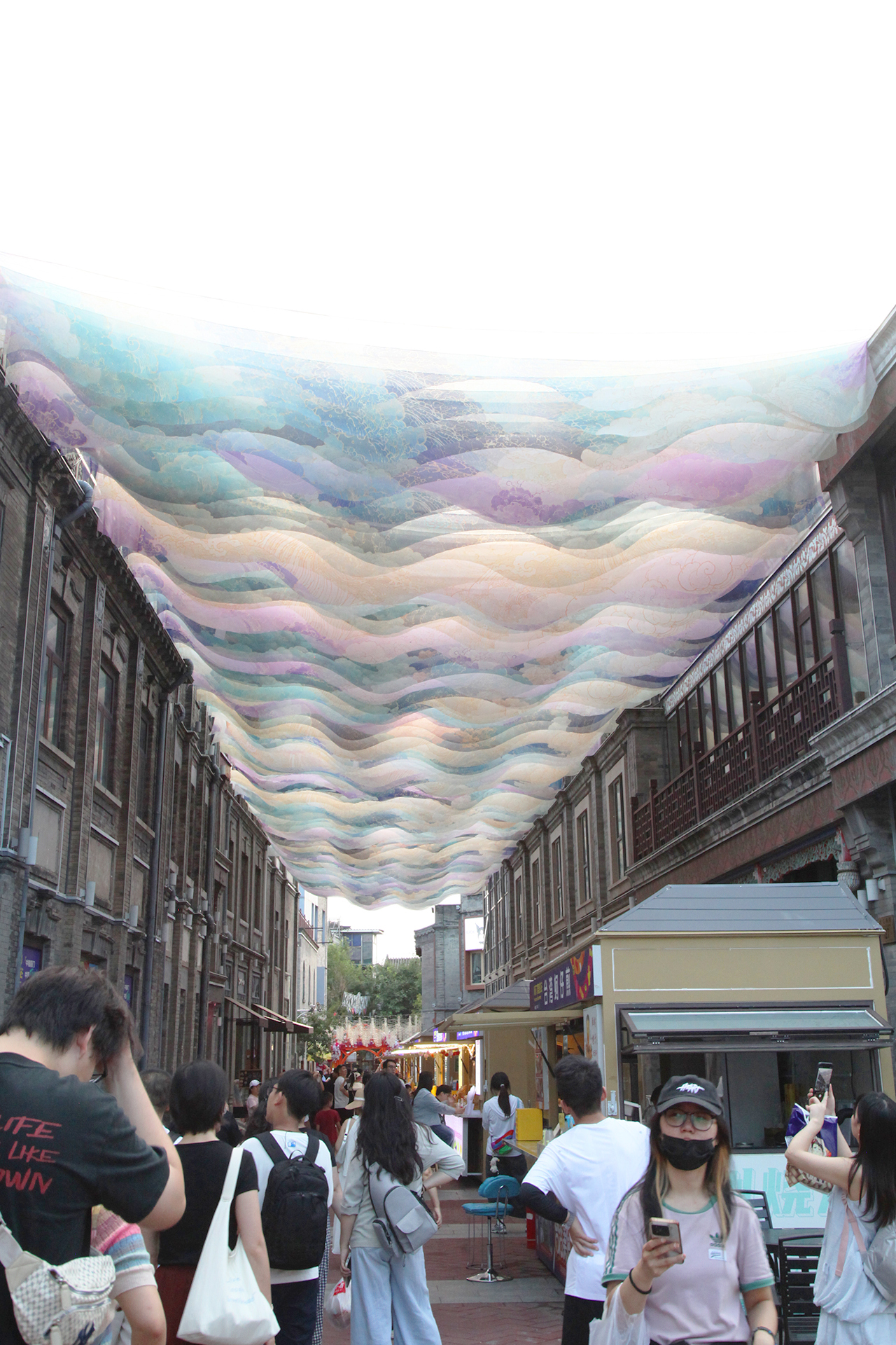 Visitors admire the art canopy in Dajiang Hutong in Beijing's historic Qianmen area. /CGTN