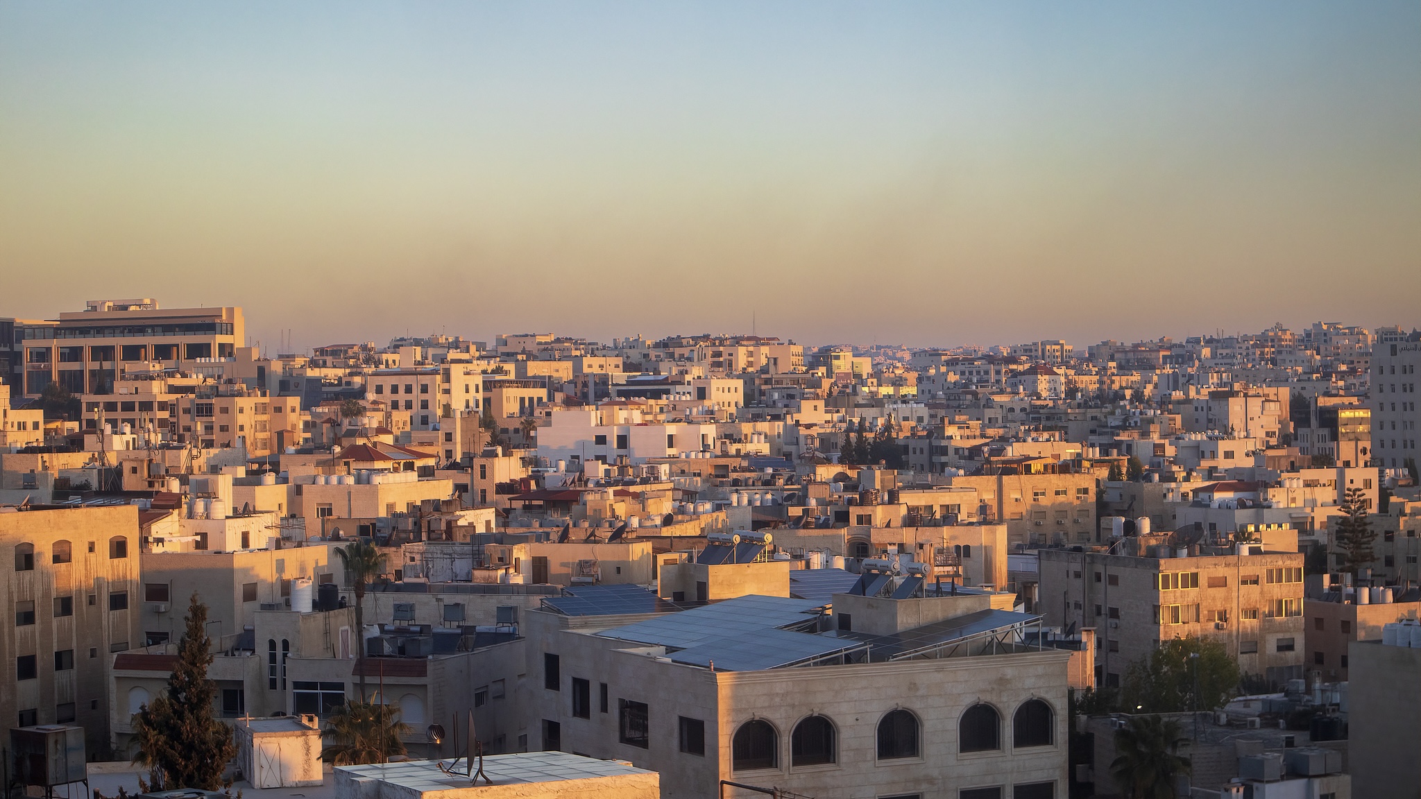 Dense residential buildings of Amman bathed in warm sunset glow, Jordan./ VCG
