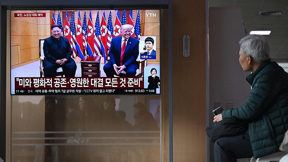 A man watches a television screen showing a news broadcast with a file photo of DPRK leader Kim Jong Un and US President Donald Trump, at a railway station in Seoul, ROK, February 26, 2026. /VCG