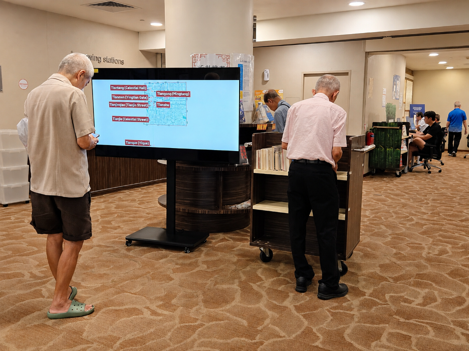 A visitor pauses at a display screen showing films and animations from the CGTN Art Series while another looks through the books on display. /CGTN