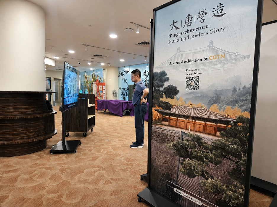 A visitor watches one of CGTN's digital films beside a CGTN Art Series exhibition banner at Chinatown Library. /CGTN