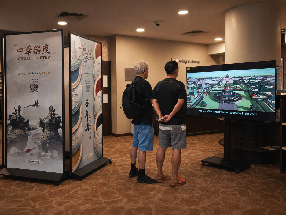Visitors stop to watch a China Crafted film at Singapore's Chinatown Library. /CGTN