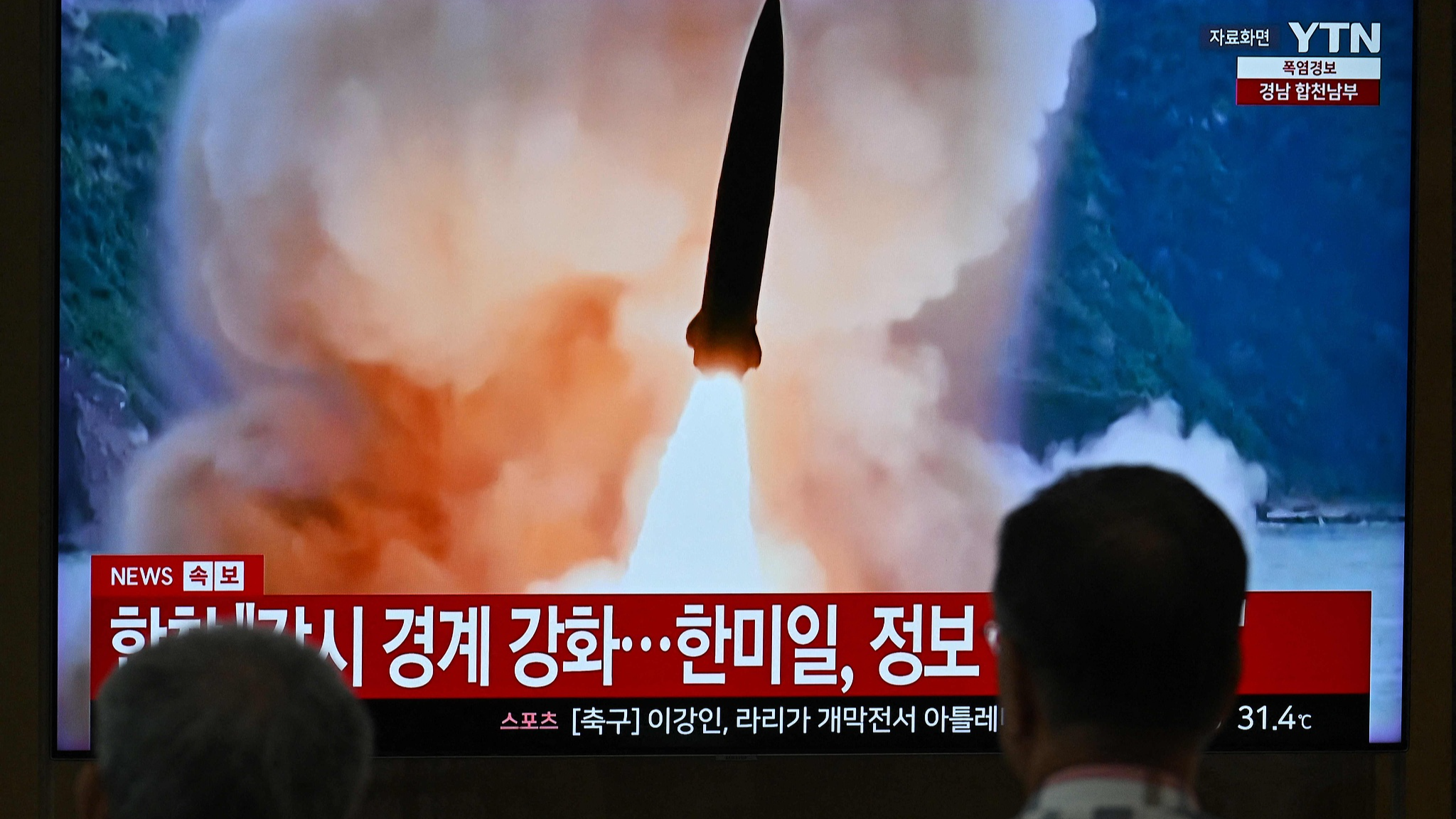 People watch a television screen showing a news broadcast with file footage of a DPRK missile test, at a train station in Seoul, August 20, 2026. /VCG