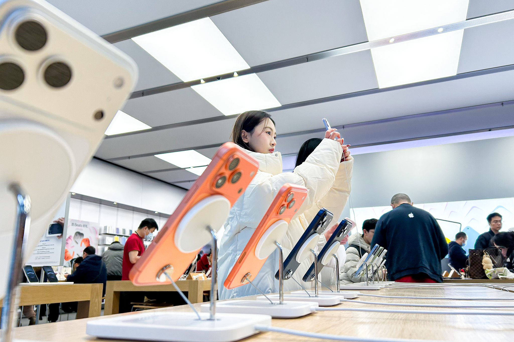 People try out smartphones at an Apple Store in Chengdu, Sichuan Province, amid China's consumer trade-in program for mobile phone purchases, January 2, 2026. /VCG