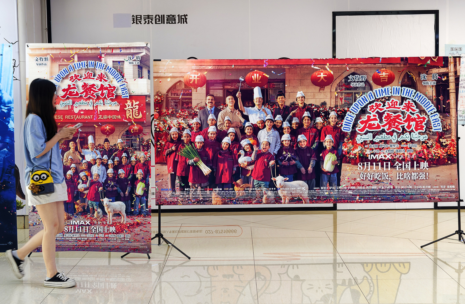 A woman walks past posters for the Chinese film 