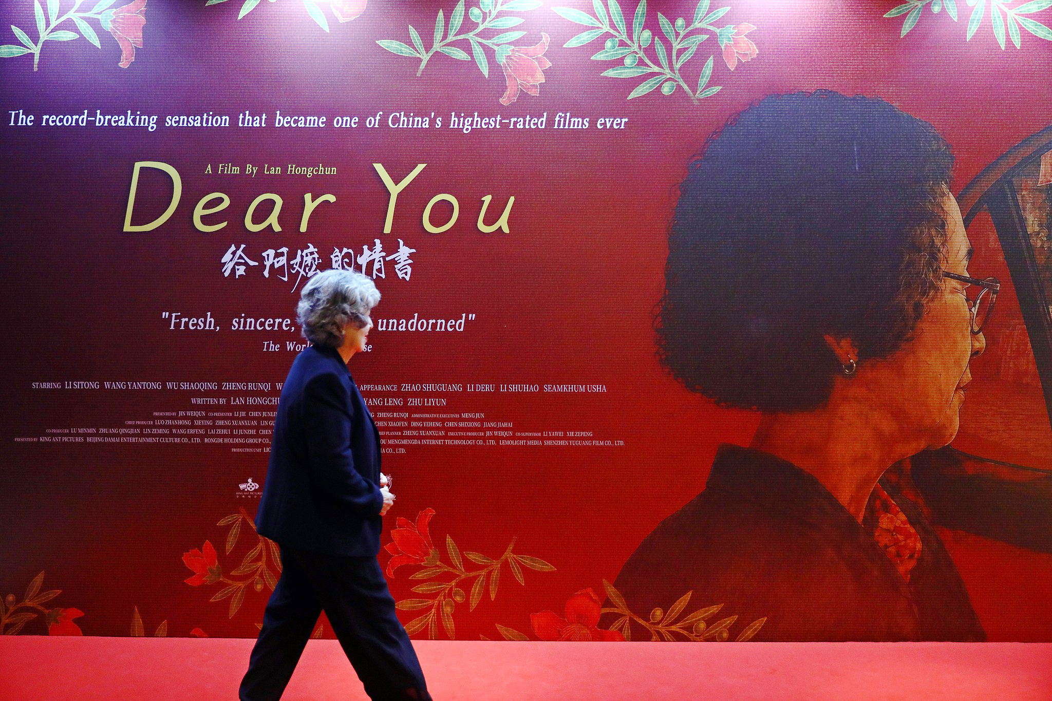 An audience member walks past a poster for the Chinese film 