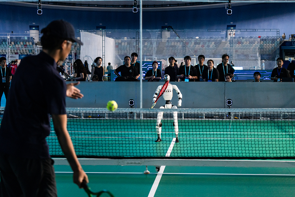 A technician plays a round of tennis with a Galbot ET 1 robot ahead of the opening of the World Humanoid Robot Games in Beijing, China, August 21, 2026. /VCG