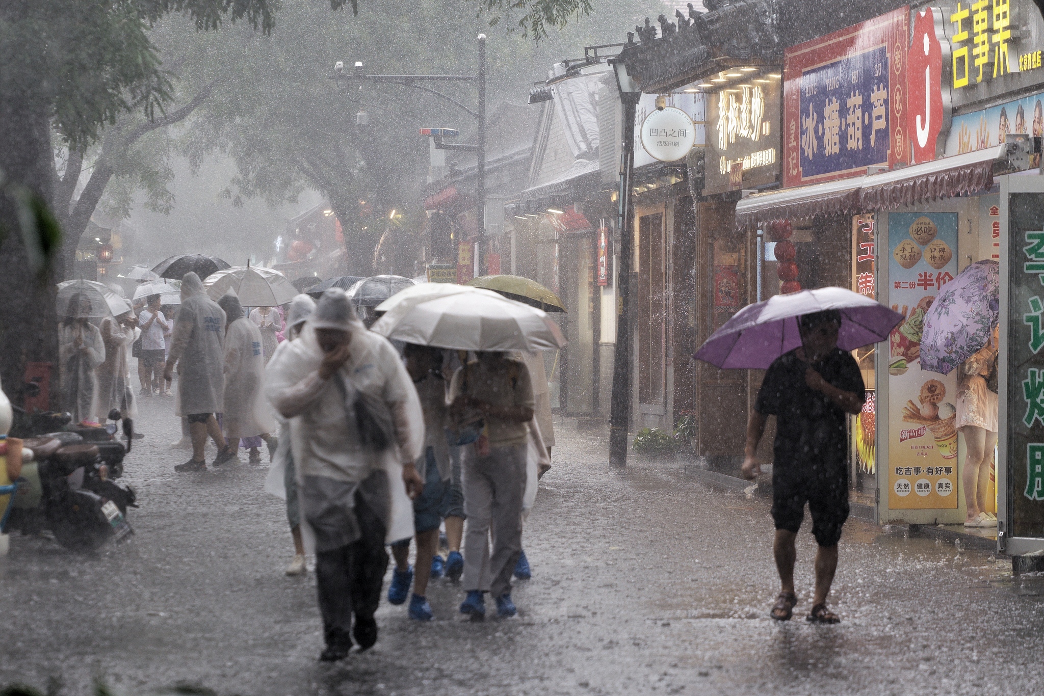 People brave the rain at Nanluoguxiang, Beijing, north China's Beijing Municipality, August 22, 2026. /VCG
