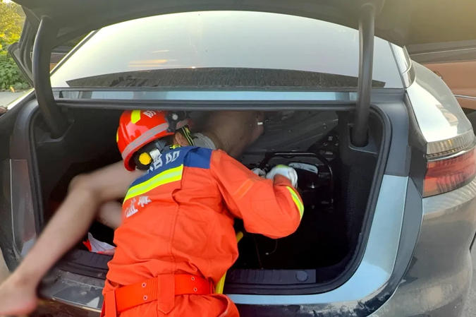 A firefighter tries to rescue a man trapped in a car trunk, Yancheng City, east China's Jiangsu Province, August 18, 2026. /Jiangsu Provincial Fire Rescue Corps