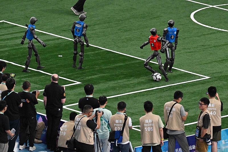 A humanoid robot dribbles past a defender during the large robot football final match of the 2nd World Humanoid Robot Games at the National Speed Skating Oval in Beijing, China, August 26, 2026. /VCG 