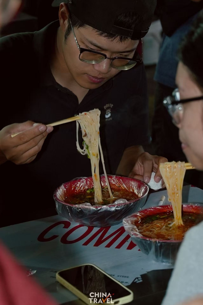 Tourists taste local food at Gongting Road night market. /CGTN