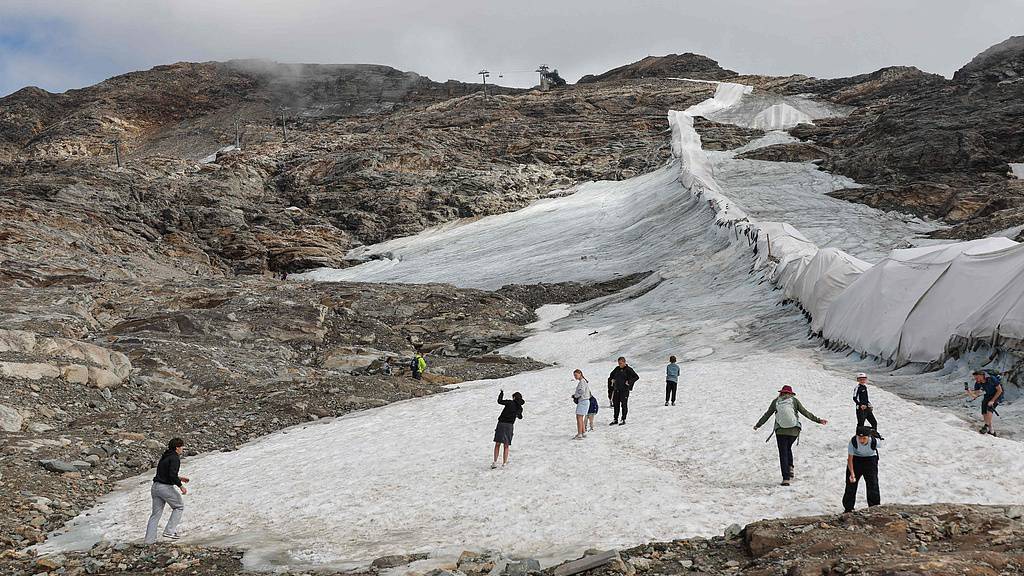 People walk beside protective fleece covering part of the Moelltal Glacier in Carinthia, Austria, on August 19, 2026, as the glacier has shrunk to a narrow strip of snow amid accelerating ice loss across the Alps, where glacier surface area has fallen 39% since 2000. /VCG