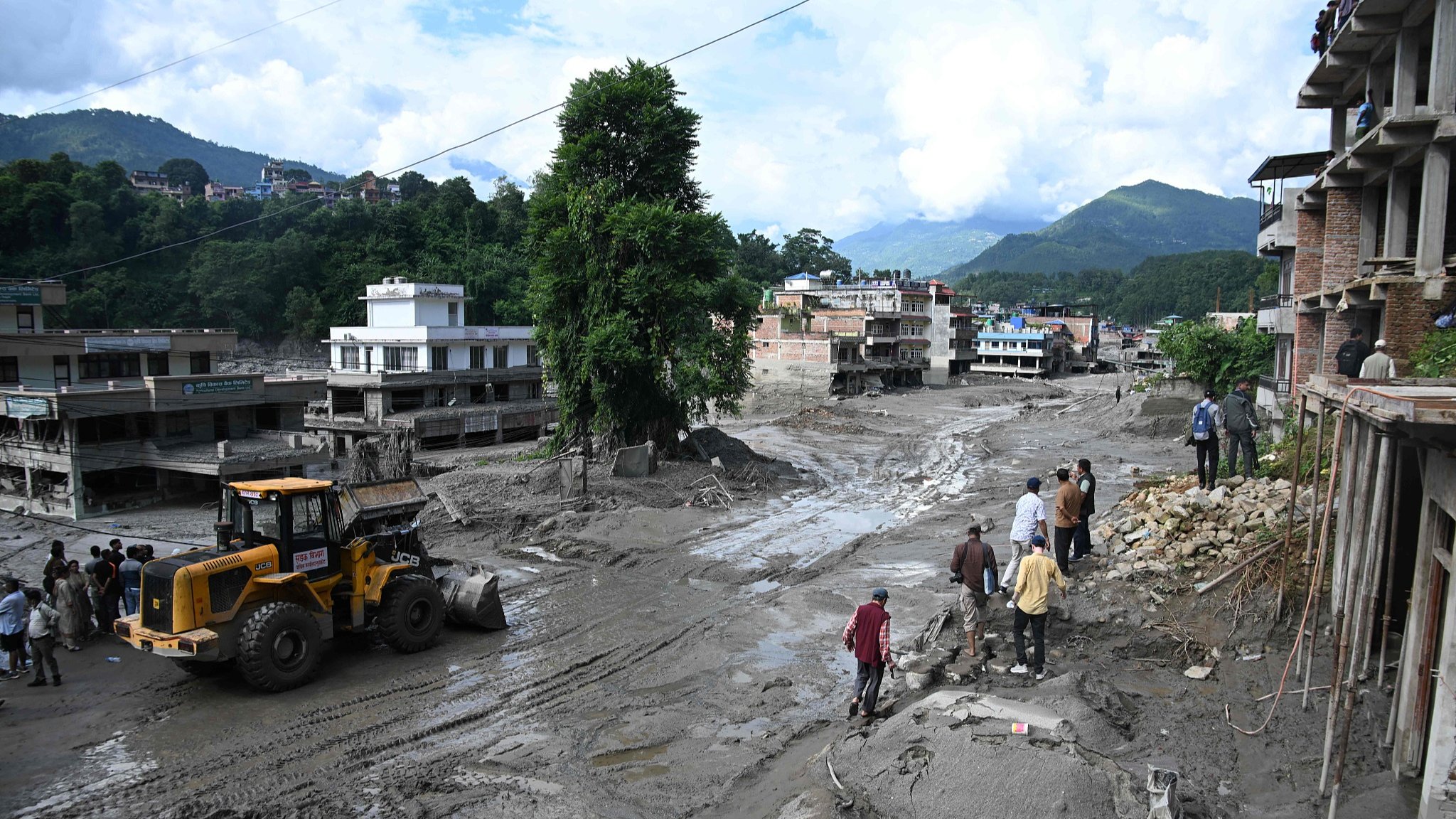 Workers use excavators to clear the mud following flash floods in Trishuli in Nepal's Nuwakot district, August 27, 2026. /VCG