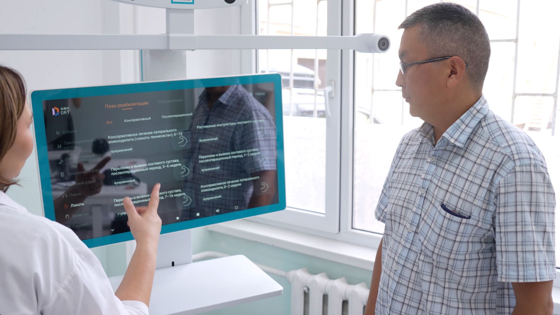 A Kyrgyz patient listens as a rehabilitation therapist explains how to use the DRT. /CGTN