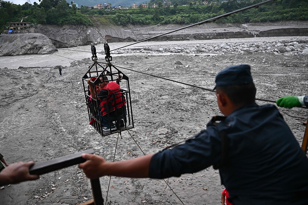 People commute across the Trishuli River via an installed zip line in the aftermath of flash floods at Trishuli Center in Nepal's Nuwakot district, September 4, 2026. /VCG