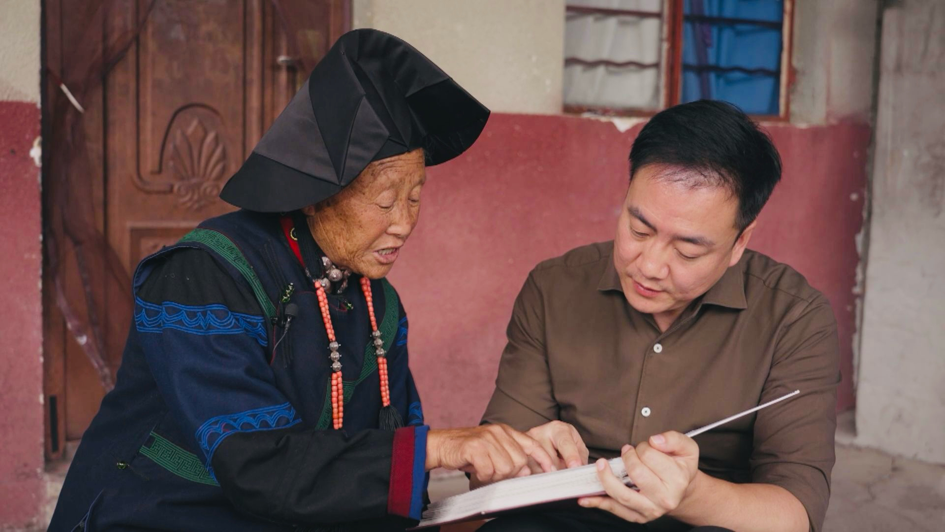 Xiaoyedan's granddaughter shares the story of the historic Yihai Alliance with a CGTN reporter through old family photographs./CGTN