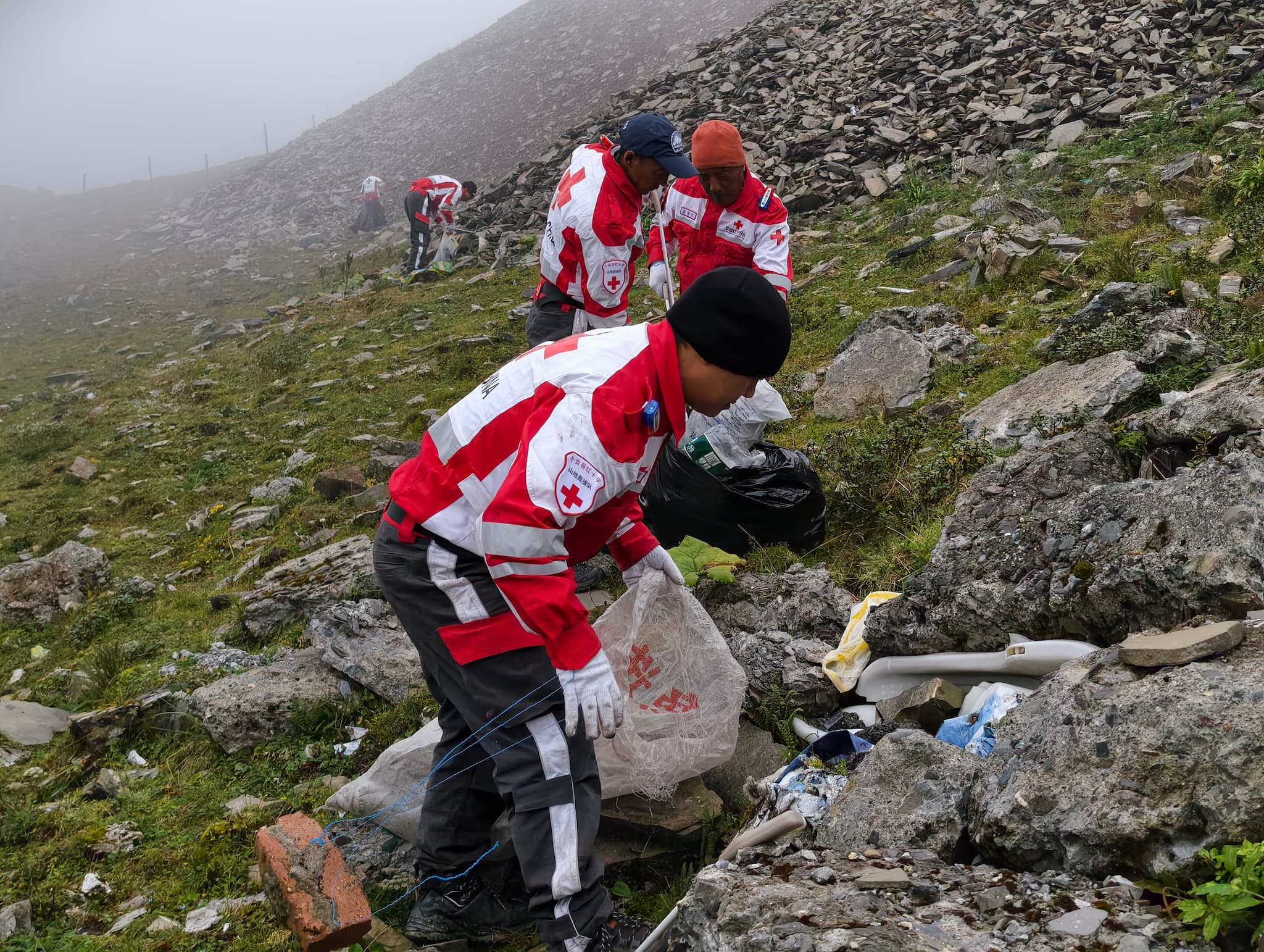 Members of the Xiaojin County Red Cross Mountain Rescue Team clear litter from the slopes of Jiajin Mountain in Xiaojin County, Sichuan Province, September 12, 2026. Yang Jinghao/CGTN