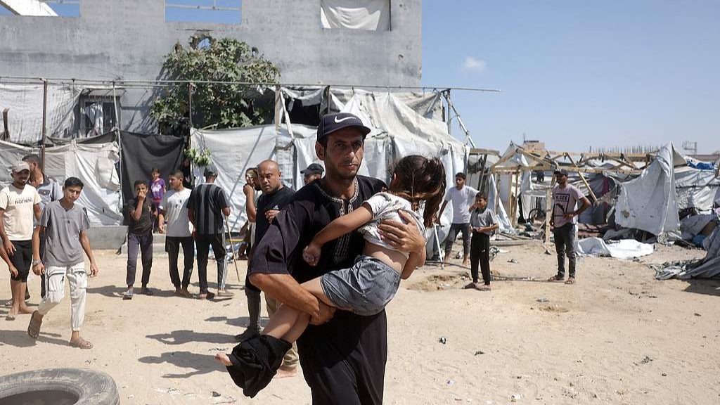 A Palestinian man carries a child following an Israeli attack in the Mawasi area in Khan Younis, Gaza Strip, September 14, 2026. /VCG